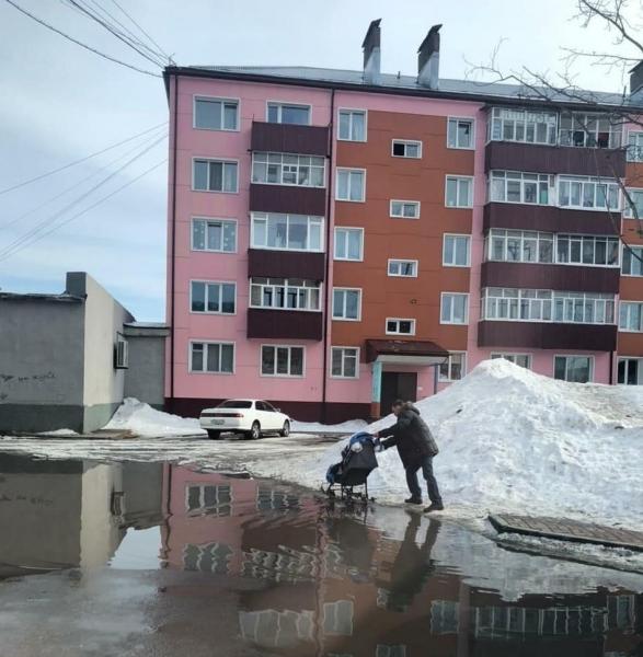 Невывезенные со придомовых территорий Поронайска кучи снега тают и приносят неудобства жителям райцентра